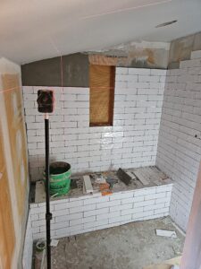 Walk in shower with white subway tiles still under construction.