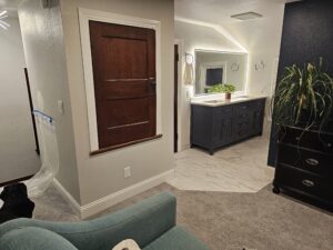Vanity area of a master bedroom bathroom suite with a heated tile floor, blue vanity, and a light up mirror.