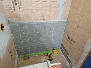 gray subway tile shower wall under construction.