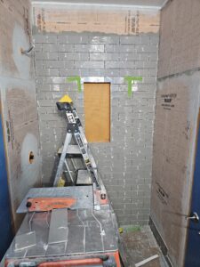 gray subway tile shower wall under construction.