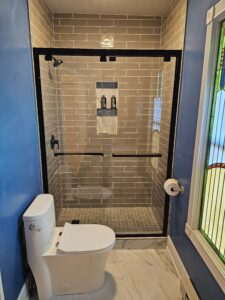 Gray subway tile shower with glass door.